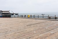 the wooden floor of a pier with a yellow surf board in the water behind it