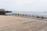 the wooden floor of a pier with a yellow surf board in the water behind it