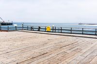 the wooden floor of a pier with a yellow surf board in the water behind it