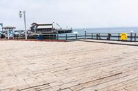 the wooden floor of a pier with a yellow surf board in the water behind it