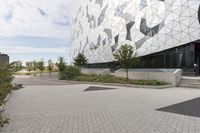 the woman is walking towards the building with a green umbrella, on her cell phone