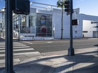 there is a woman walking along the street next to the traffic light next to a shopping center