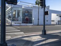 there is a woman walking along the street next to the traffic light next to a shopping center