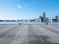 a woman walks on a pier while two pigeons sit in front of her next to water