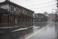 a woman walks through an alley in the rain holding an umbrella on a rainy day