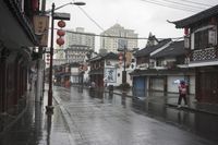 a woman walks through an alley in the rain holding an umbrella on a rainy day