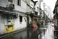 a woman walks through an alley in the rain holding an umbrella on a rainy day