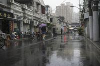 a woman walks through an alley in the rain holding an umbrella on a rainy day