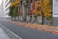 a woman is walking down the street, with leaves all over her body, in front of an old building