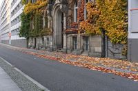 a woman is walking down the street, with leaves all over her body, in front of an old building