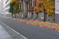 a woman is walking down the street, with leaves all over her body, in front of an old building