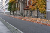 a woman is walking down the street, with leaves all over her body, in front of an old building