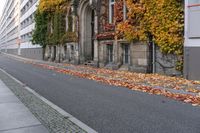 a woman is walking down the street, with leaves all over her body, in front of an old building