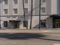 a woman is walking by the sidewalk at the hotel entrance area on a sunny day