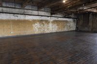 an empty room with wood floors and exposed ceilinging and brick walls the room is full of wooden floors