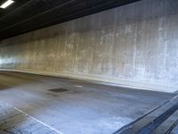 a skateboarder is riding under a large bridge by himself in a parking garage