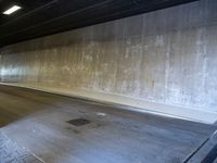 a skateboarder is riding under a large bridge by himself in a parking garage