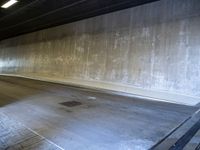 a skateboarder is riding under a large bridge by himself in a parking garage