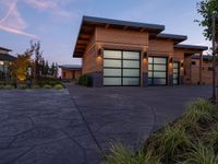 a home with stone driveway and modern garages at sunset with sky in the background