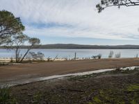 a sandy road next to a lake with no traffic on it and lots of water