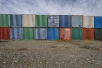 a large pile of colorful stacked shipping containers is next to each other on a gravel ground