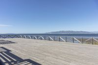 a balcony is overlooking a lake in the distance and mountains in the background on the right