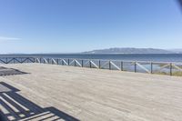 a balcony is overlooking a lake in the distance and mountains in the background on the right