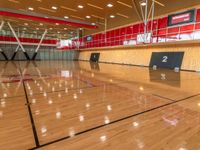 a wooden basketball court surrounded by glass walls and beams with red walls above a red wall