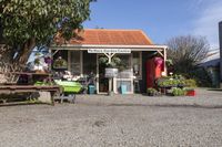 the wooden benches are sitting at the stand with the plants outside of the store in the sunshine