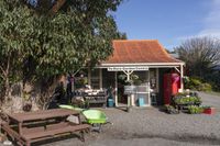 the wooden benches are sitting at the stand with the plants outside of the store in the sunshine