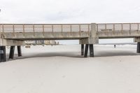 a wooden bridge across the beach, leading to a sandy area with tall sand dunes