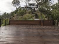 a wooden deck and steps leading up to the bottom deck of a home with a view of trees around it