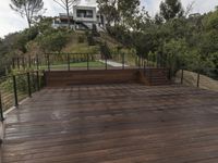 a wooden deck and steps leading up to the bottom deck of a home with a view of trees around it