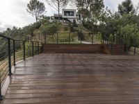 a wooden deck and steps leading up to the bottom deck of a home with a view of trees around it