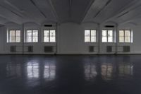 large empty room with several windows that are opened up and there is the floor tileed