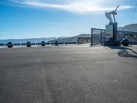 the parking area is empty with people standing and sitting around it's side near an ocean