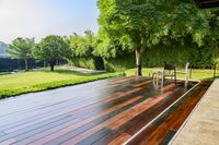 wooden patio with chair and table overlooking a lush green field outdoors setting with pool and spa