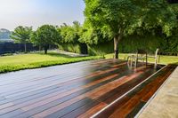 wooden patio with chair and table overlooking a lush green field outdoors setting with pool and spa