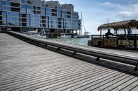 a wooden platform that is next to boats by the water in front of some buildings