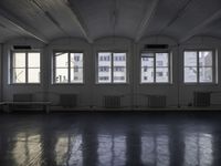 a black and white picture of a room full of windows and benches by the window