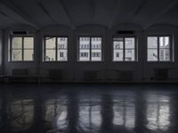 a black and white picture of a room full of windows and benches by the window