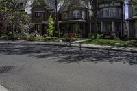 an intersection with a large row of houses, trees and bushes around it, and some trees