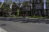 an intersection with a large row of houses, trees and bushes around it, and some trees