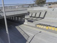 a yellow and black trashcan sitting on the side of an overpass next to concrete columns