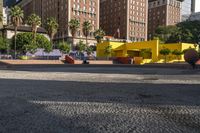 a yellow brick building sitting in the middle of a city street with tall buildings and some traffic