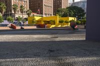 a yellow brick building sitting in the middle of a city street with tall buildings and some traffic