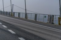 the side of a bridge crossing over the ocean, with a bike and pedestrians in traffic