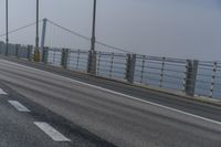 the side of a bridge crossing over the ocean, with a bike and pedestrians in traffic