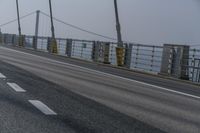 the side of a bridge crossing over the ocean, with a bike and pedestrians in traffic