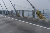 the side of a bridge crossing over the ocean, with a bike and pedestrians in traffic